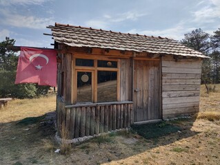Rural Resilience: A Rustic Cabin with the Turkish Flag, Symbolizing National Pride and Simplicity Amidst Nature's Embrace"