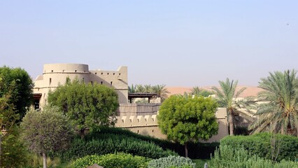 Desert oasis with swaying palms and sandy horizon. Historic buildings blend ancient elegance with traditional charm, offering stunning views and emphasizing heritage conservation.