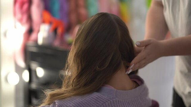 The master has divided the hair into two parts, and puts one part in a ponytail. Preparation for braiding pigtails from pink kanekalon. High quality 4k footage