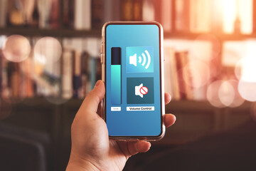 Close-up view of hand turning down the volume of smartphone in silent or mute mode activated.