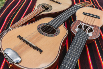 Naklejka premium Traditional Andean instruments elegantly arranged on a striped textile. The Charango, Mandolin, and Bandolina are artfully crossed, highlighting their fine details and cultural significance.