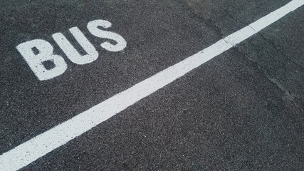 Close-up of a bus lane marking on asphalt, showcasing the white paint and textured road surface. Perfect for urban, transportation, or city life themes