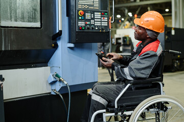 Industrial worker in wheelchair operating complex machinery in manufacturing facility, looking focused and engaged, demonstrating skill and efficiency, emphasizing inclusive work environment