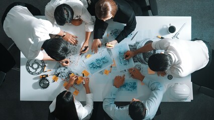 Top down aerial view of smart engineer team working together to design turbine engine. Professional...