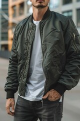 A man wearing a green bomber jacket stands on a city street, with a modern urban backdrop