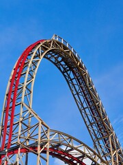 A close-up image of a red rollercoaster track and the blue sky in the background in the amusement park.