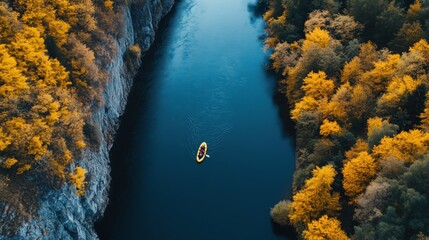 Top view of a rafting boat navigating a mountain river surrounded by vibrant yellow autumn foliage. Perfect for active leisure and travel concepts,
