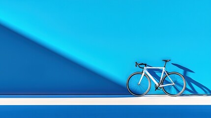 Fototapeta premium A bike resting against a blue wall with shadows on its back and front ends