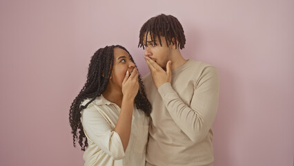 Man and woman couple in casual clothes express surprise against a plain pink background