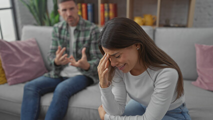 Obraz premium Distressed woman and concerned man discussing issues on sofa in a living room setting