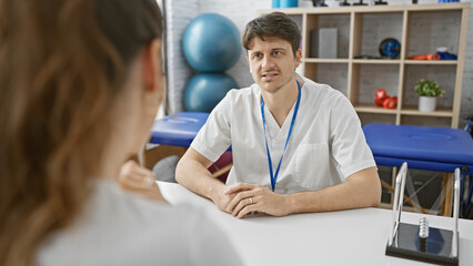 Obraz premium A male physiotherapist consults with a female patient in a modern rehabilitation clinic.