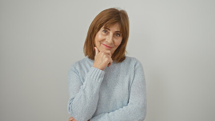 Confident mature woman with short hair and sweater posing thoughtfully against a white background.