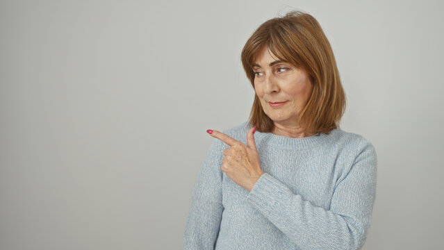 Mature woman pointing sideways against a white background, embodying consideration and elegance.