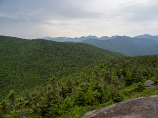 View from the summit of Cascade Mountain, Lake Placid, New York State, with rock in the foreground and surrounding Adirondack forest landscape.