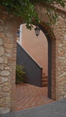 Obraz premium An archway with a hanging lantern leads to a stairway, evoking mediterranean architecture and charming ambiance.