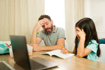 Anxious dad comforting his upset daughter while assisting her with her homework