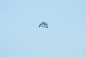 Two people fly in Spain on a parachute against the backdrop of the sea in Spain