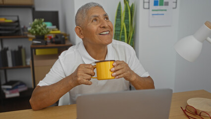 A handsome, grey-haired, hispanic man enjoying coffee in an office setting, captured in an indoor workspace environment with a mature and elderly ambiance.