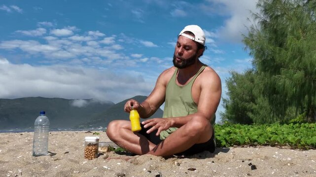 Man on a sunny day at the beach having a picnic, eating and drinking water. Outdoor concept.