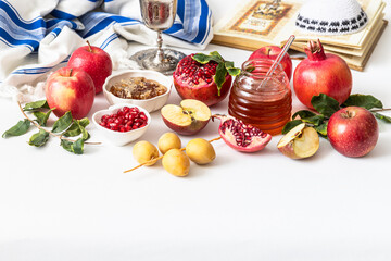 Jewish holiday Rosh Hashana festive table setting with plate, honey, apple ,pomegranates, dates, book of hebrew prayers, kiddush cup