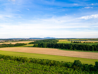 A stunning drone view of Hrusovany u Brna, showcasing the charming town, surrounding vineyards, and a distant, scenic view of the Palava Hills.