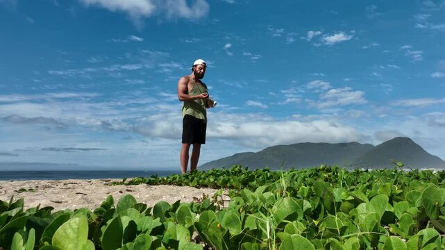 Man on a sunny day at the beach having a picnic, eating and drinking water. Outdoor concept.