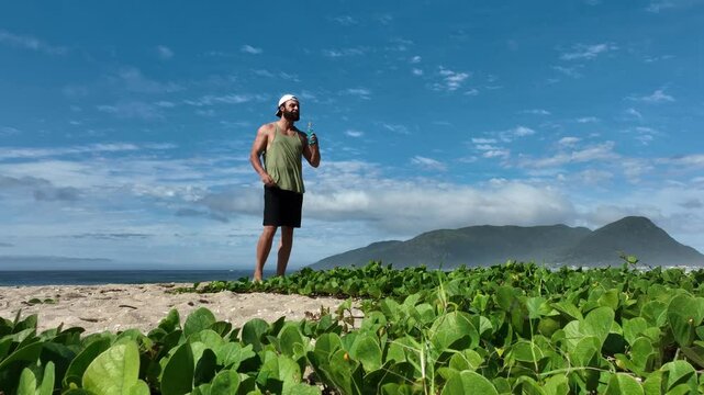 Man on a sunny day at the beach having a picnic, eating and drinking water. Outdoor concept.