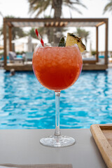Frozen strawberry margarita cocktail at the edge of a resort pool. Concept of luxury vacation. Outdoor pool background. Horizontal, wide screen format