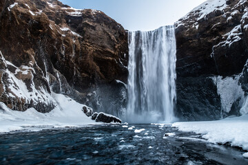 Winter Waterfall Amidst Snowy Cliffs