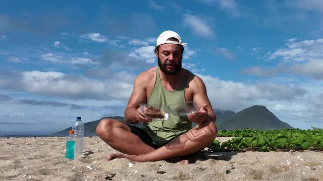 Man on a sunny day at the beach having a picnic, eating and drinking water. Outdoor concept.