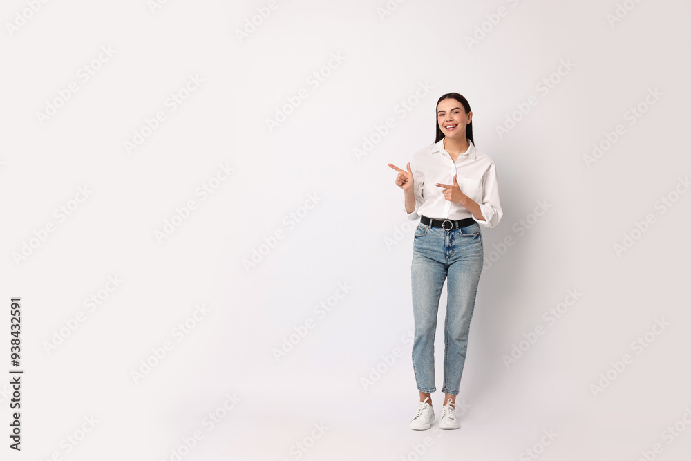 Poster Smiling woman pointing at something on white background. Space for text