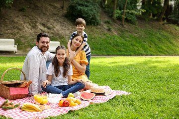 Family picnic. Happy parents and their children spending time together on green grass outdoors....