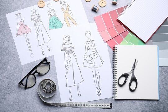 Sketches of stylish clothes and other fashion designer`s supplies on grey table, flat lay