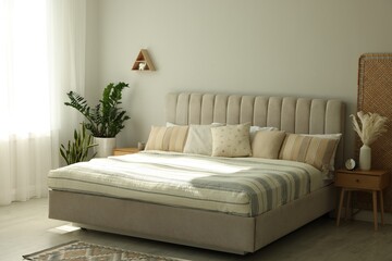 Large bed, houseplants and bedside table in stylish room