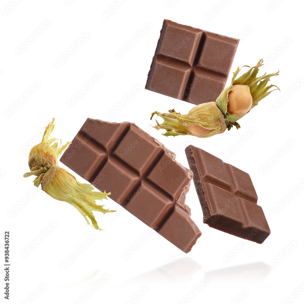 Poster Pieces of tasty chocolate and hazelnuts falling on white background