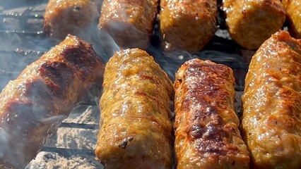 Meatballs on grill. Man fries patties on barbecue. Spicy minced meat rolls BBQ. Inegöl or Tekirdag Meatballs a type of grilled meat dish famous in Turkey made from minced lamb or beef Outdoor Close up