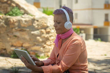 Cancer survivor using tablet with headphones in tranquil outdoor setting