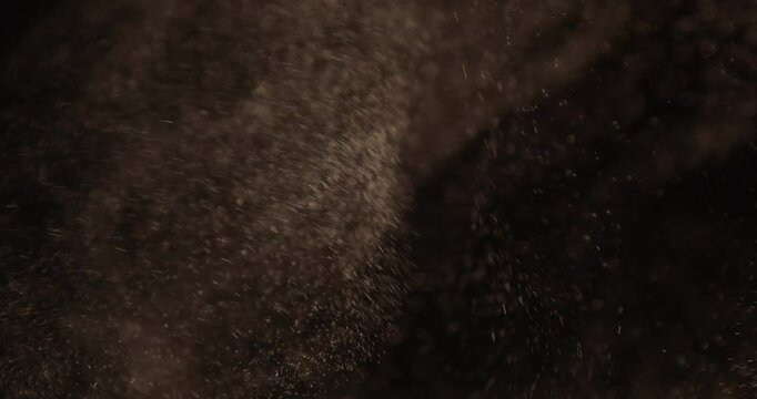 Particles close-up flying in the air over black background. Sparks, glitter, powder or dust concept footage. 4K UHD video.