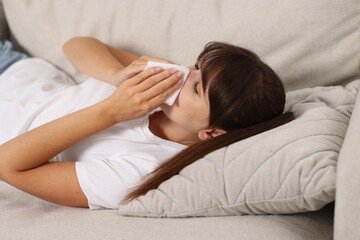 Woman with napkin suffering from sinusitis on sofa at home