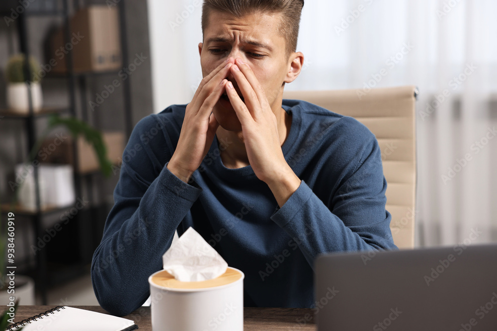 Canvas Prints Young man with tissue suffering from sinusitis at wooden table indoors