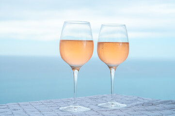 Summer time in Provence, two glasses of cold rose wine with blue sea view on background, French Riviera near Menton, south of France