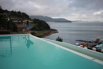 Young woman watching sunrise at a resort with a swimming pool overlooking the sea in Yeosu