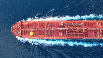 Top-down view of a crude oil tanker speeding through calm waters with trails of foam around her....