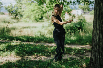 Girl performing modern dance in nature, expressing grace and passion. Captured with lush green background and natural light.