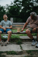 A father and son share a relaxed moment playing with building blocks on a bench in a scenic park. The child appears delighted while bonding with his dad in nature.