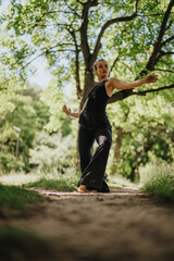 Lovely girl dancing in nature, executing modern dance movements amongst lush, green surroundings.