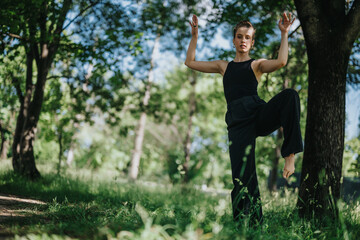 Lovely girl dancing in nature, executing elegant modern dance moves surrounded by a lush green...