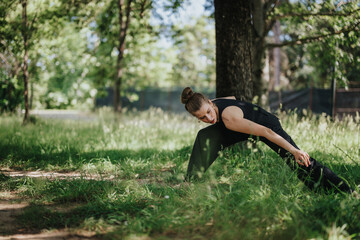 A young woman gracefully dancing in nature, showcasing a modern dance pose amidst a lush green outdoor setting.