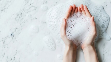 Top view of female hands washing with soap, surrounded by bubble foam on a white background, highlighting hygiene, cleanliness, and self-care.