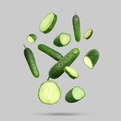 Many ripe cucumbers falling on grey background